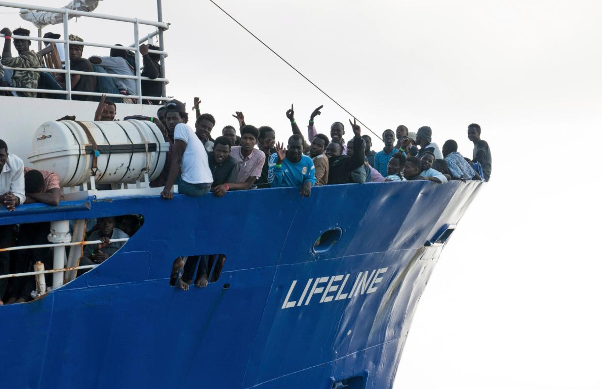 Rescued: migrants wave from aboard ship operated by the German NGO Mission Lifeline: AP