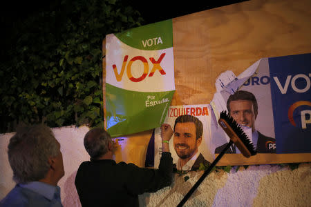 Members of Spain's far-right party VOX put up a campaign poster, while main candidates for Spanish general elections debate during a live televised debate ahead of general elections in Madrid, outside a polling station in Ronda, southern Spain April 22, 2019. REUTERS/Jon Nazca