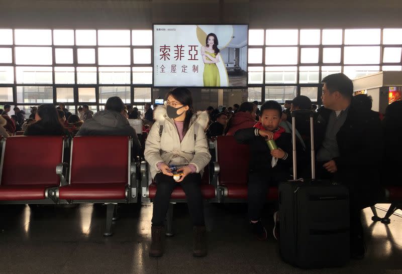 A woman wearing a mask is seen at a waiting area for a train to Wuhan at the Beijing West Railway Station, in Beijing