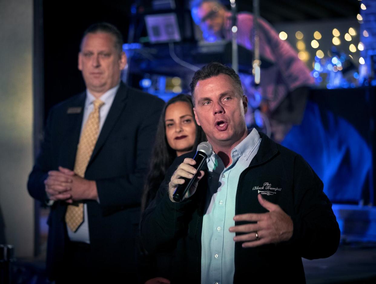 Huntington Beach City Atty. Michael Gates speaks into a microphone as two people listen in the background.