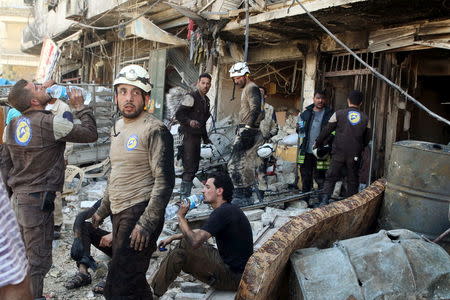 Civil defense members rest amid rubble of damaged buildings after an airstrike on the rebel-held Tariq al-Bab neighborhood of Aleppo, Syria. REUTERS/Abdalrhman Ismail