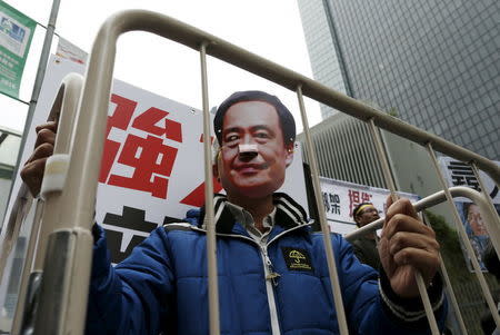 A demonstrator wears a mask depicting Causeway Bay Books shareholder Lee Bo during a protest over the disappearance of booksellers, in Hong Kong, China January 10, 2016. REUTERS/Tyrone Siu