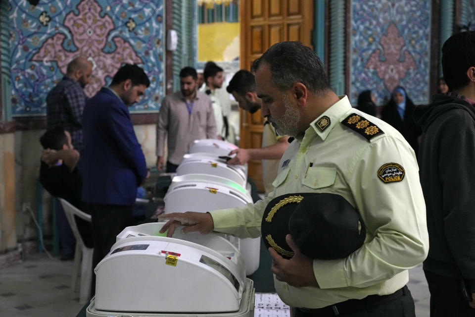 An Iranian police colonel votes for the parliamentary runoff elections at a polling station in Tehran, Iran, Friday, May 10, 2024. Iranians voted Friday in a runoff election for the remaining seats in the country's parliament after hard-line politicians dominated March balloting. (AP Photo/Vahid Salemi)