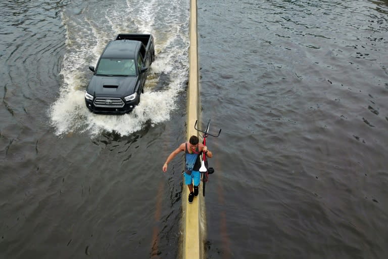 A man walks on a highway divider while carrying his bicycle in the aftermath of Hurricane Maria in San Juan