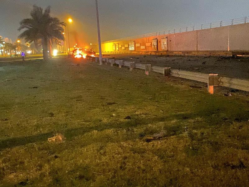 Burning debris are seen on a road near Baghdad International Airport