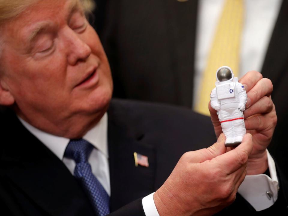 donald trump holds up a small astronaut figurine