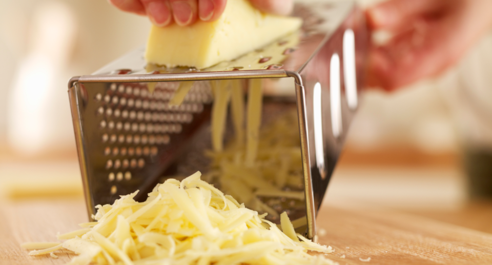 Cheese being grated on a food grater. 