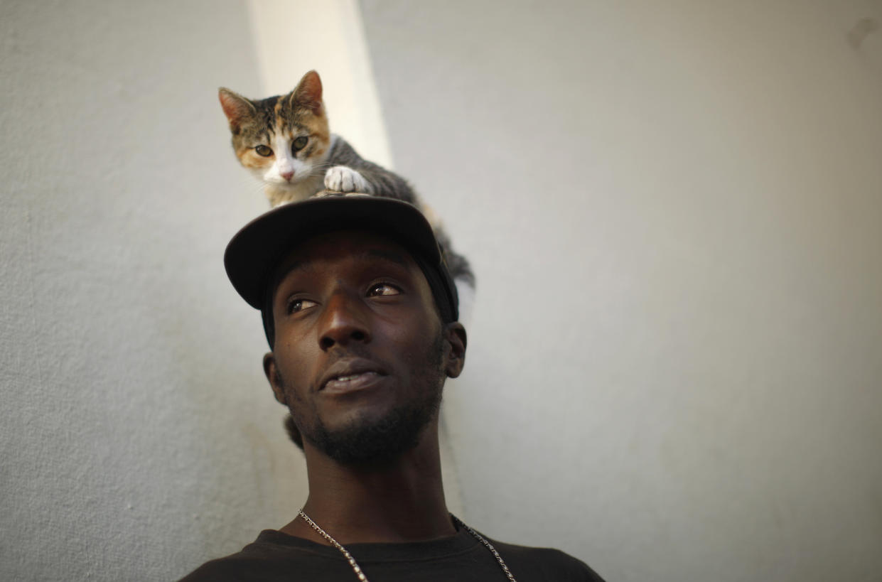 Michael Norton, 23, who does not have health insurance, stands with his cat M.J. at a Covered California event which marks the opening of the state's Affordable Healthcare Act, commonly known as Obamacare, health insurance marketplace in Los Angeles, California, October 1, 2013. Technical glitches and heavy internet traffic slowed Tuesday's launch of new online insurance exchanges at the heart of President Barack Obama's healthcare reform, showcasing the challenge of covering millions of uninsured Americans. REUTERS/Lucy Nicholson (UNITED STATES - Tags: ANIMALS POLITICS HEALTH)