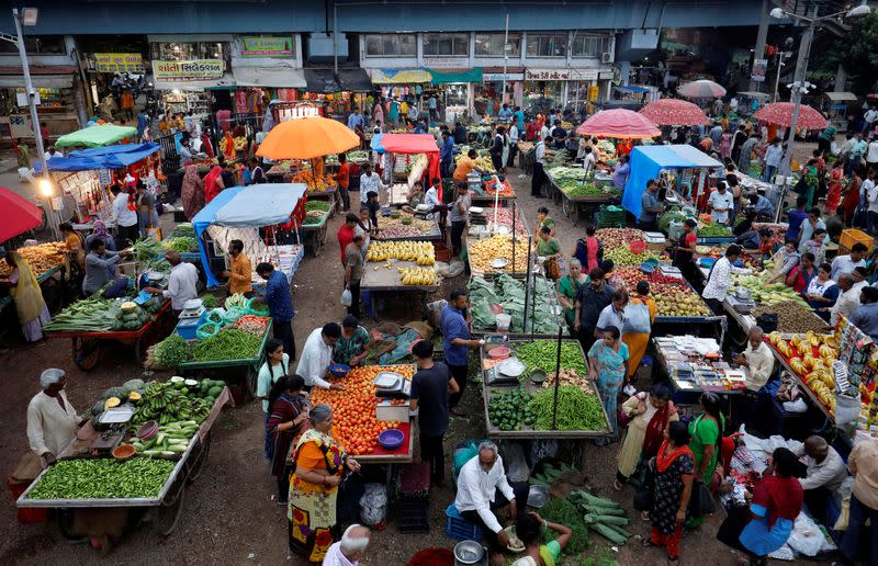 FILE PHOTO: Customers buy fruits and vegetables at an open air evening market in Ahmedabad