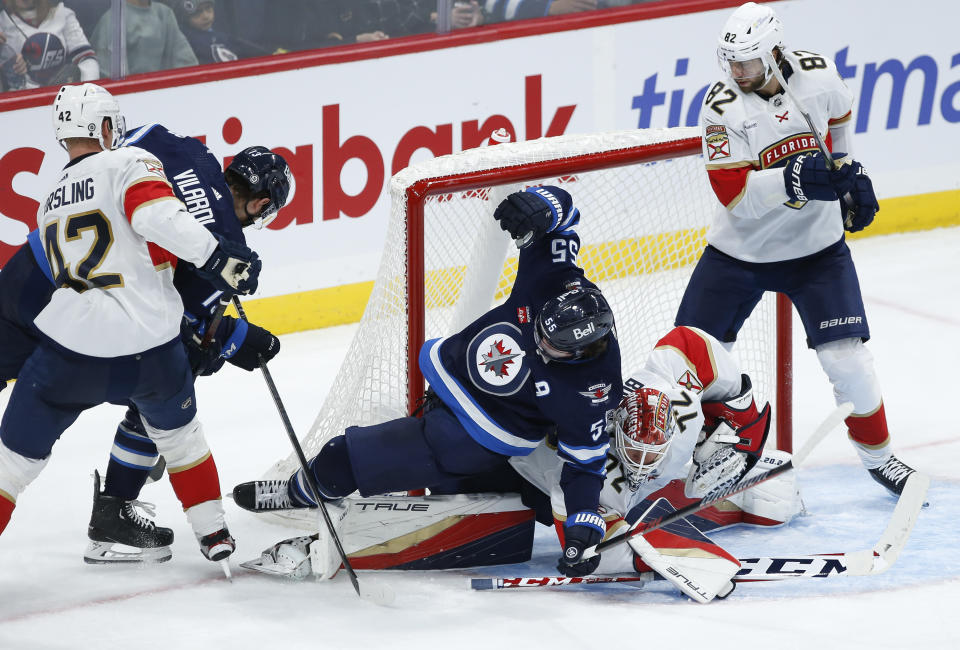 Winnipeg Jets' Mark Scheifele (55) crashes into Florida Panthers goaltender Sergei Bobrovsky (72) as Panthers' Kevin Stenlund (82) defends during third-period NHL hockey game action in Winnipeg, Manitoba, Saturday, Oct. 14, 2023. (John Woods/The Canadian Press via AP)