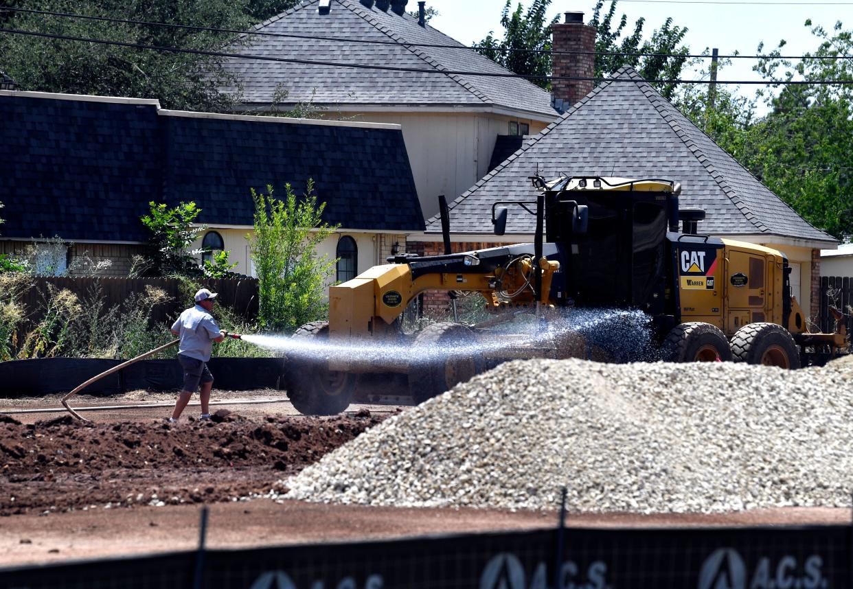 A construction worker sprays water on the ground as the site of a new Starbuck’s on Buffalo Gap Road is cleared Thursday.
