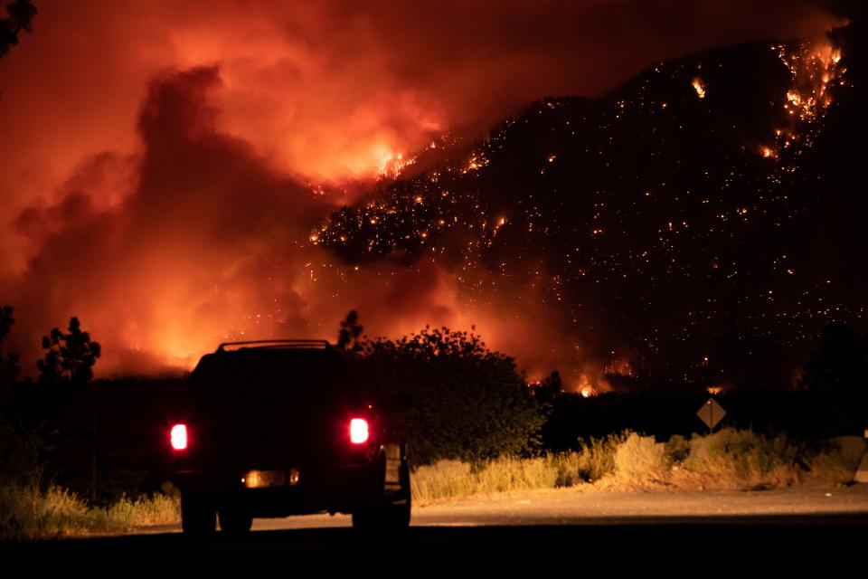 A motorist watches wildfire burn in Lytton, Canada, after the town saw a record temperature for the country (AP)