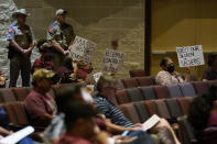 Parents and family hold protest signs during a special meeting of the Board of Trustees of Uvalde Consolidated Independent School District where parents addressed last month's shooting at Robb Elementary School, Monday, July 18, 2022, in Uvalde, Texas. (AP Photo/Eric Gay)
