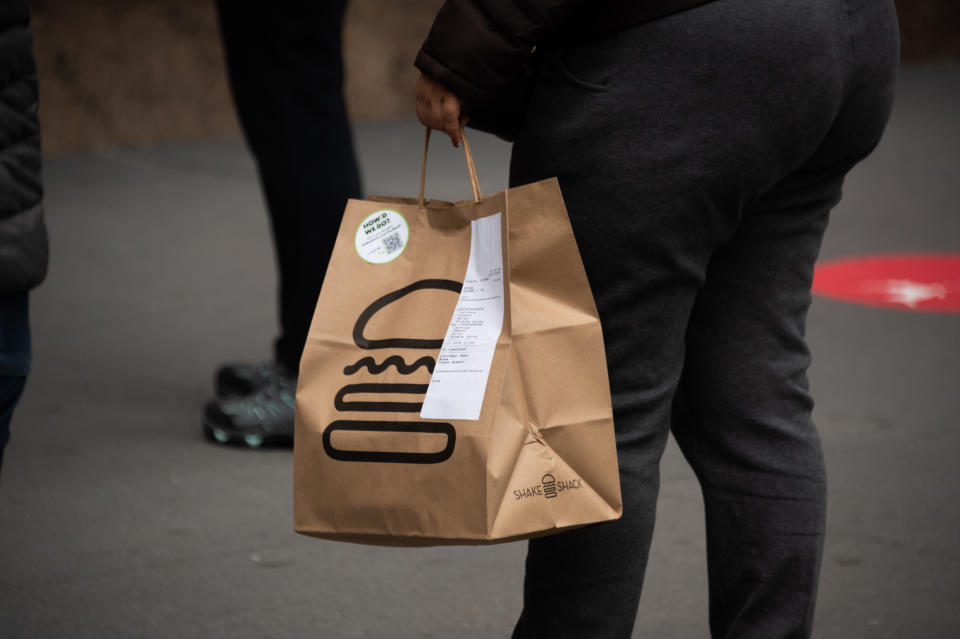 NEW YORK, NEW YORK - DECEMBER 02: A person carries a Shake Shack takeout bag in Herald Square as the city continues the re-opening efforts following restrictions imposed to slow the spread of coronavirus on December 02, 2020 in New York City. The pandemic has caused long-term repercussions throughout the tourism and entertainment industries, including temporary and permanent closures of historic and iconic venues, costing the city and businesses billions in revenue. (Photo by Noam Galai/Getty Images)