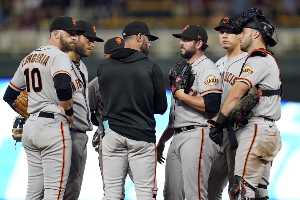San Francisco Giants manager Gabe Kapler, center, talks with relief pitcher Dominic Leone, center right, during the 10th inning of a baseball game against the Minnesota Twins, Saturday, Aug. 27, 2022, in Minneapolis. (AP Photo/Abbie Parr)