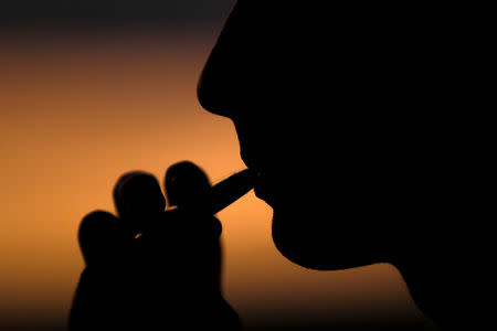 A young man smokes a Suorin Drop electronic cigarette in this picture illustration taken September 14, 2018. REUTERS/Mike Blake/Illustration