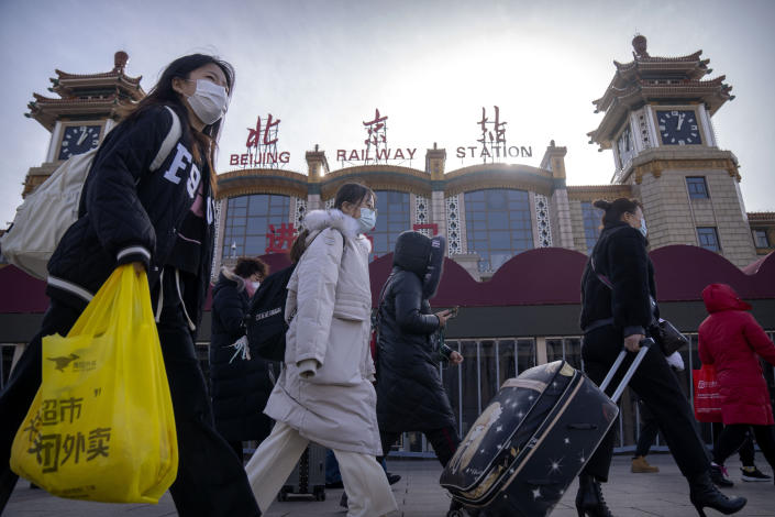 Travelers wearing face masks walk past the entrance of the Beijing Railway Station in Beijing, Saturday, Jan. 14, 2023. Millions of Chinese are expected to travel during the Lunar New Year holiday period this year. (AP Photo/Mark Schiefelbein)