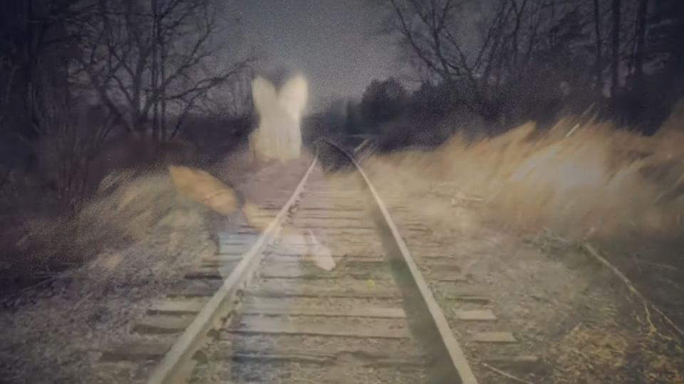 An image of a man in a bunny mask is overlaid with an image of a railroad track