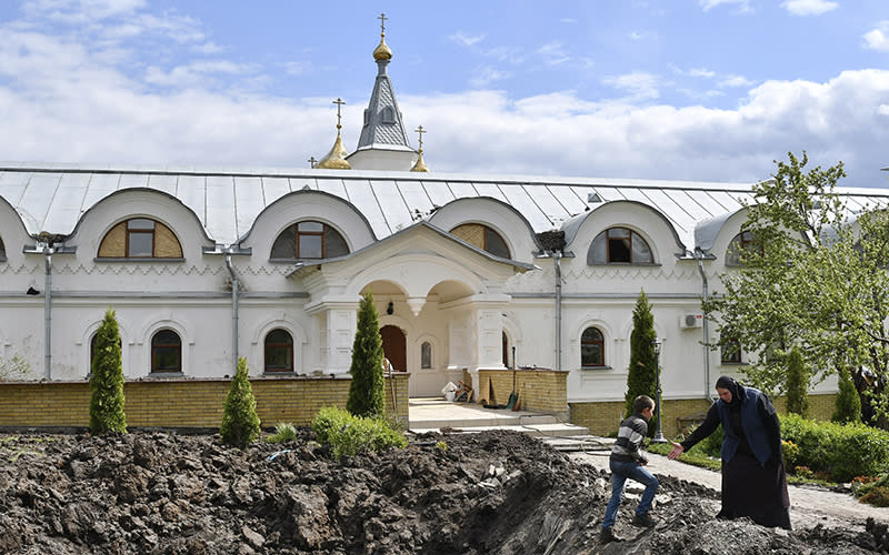 Orthodox Sister Evdokia holds out a hand to help a boy up from a crater left after an explosion near the entrance of a church