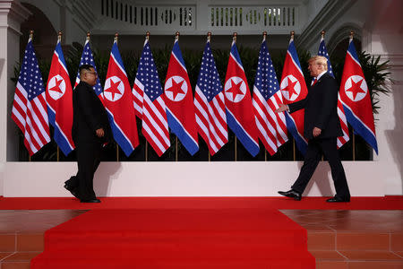 U.S. President Donald Trump and North Korean leader Kim Jong Un walk to shake hands at the Capella Hotel on Sentosa island in Singapore June 12, 2018. REUTERS/Jonathan Ernst