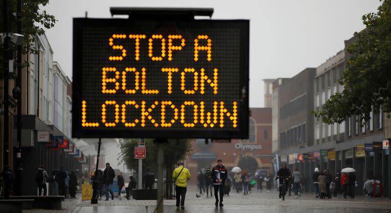 People walk past an information board following the outbreak of the coronavirus disease (COVID-19) in Bolton, Britain