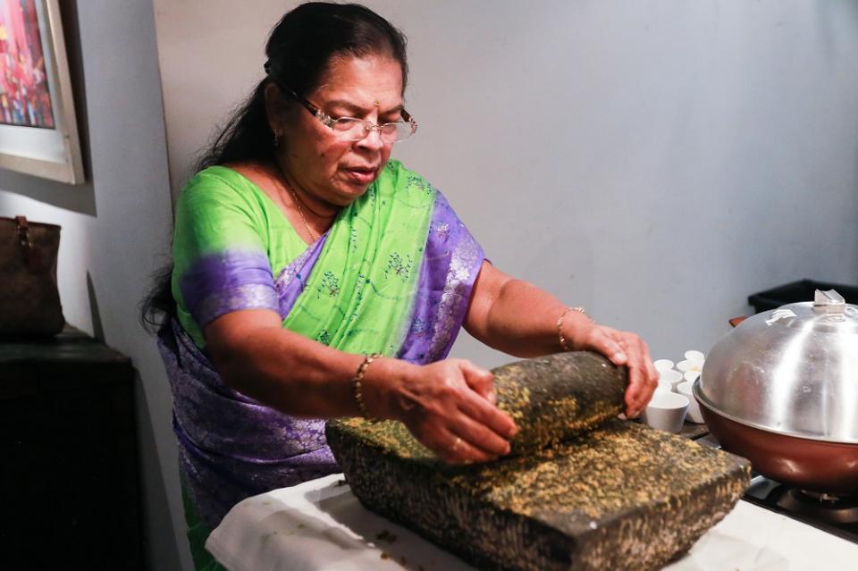 Parvathy using the traditional Sri Lankan grinding stone to make a sambal paste. — Picture by Ahmad Zamzahuri