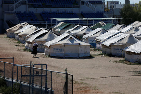 A migrant woman makes her way next to tents set at the old baseball venue of the former Hellenikon Olympic complex, which is used as a shelter for refugees and migrants, in Athens, Greece, July 13, 2016. Picture taken July 13, 2016. REUTERS/Alkis Konstantinidis