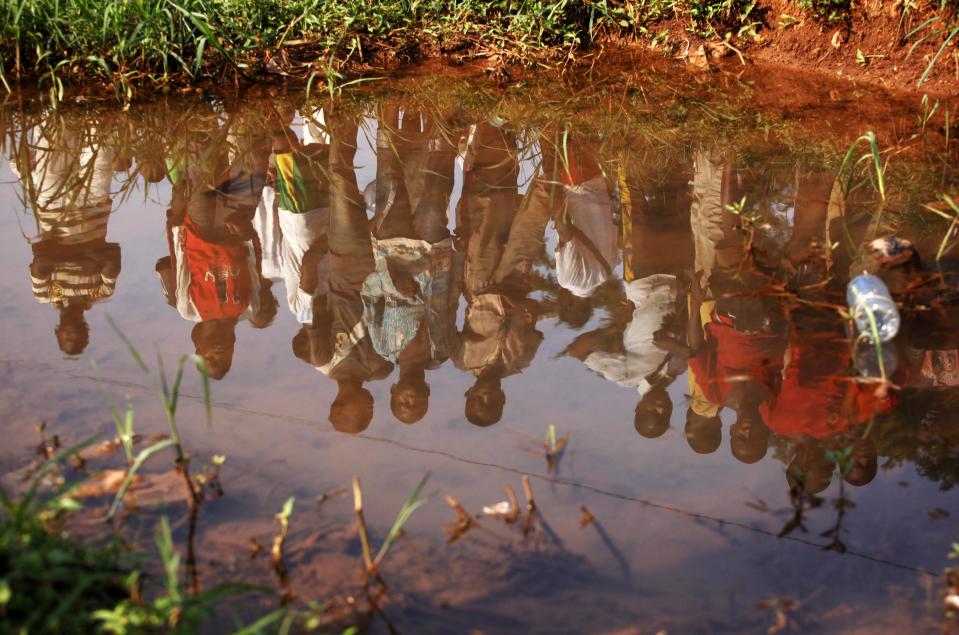 Men are reflected in the water in Bangui