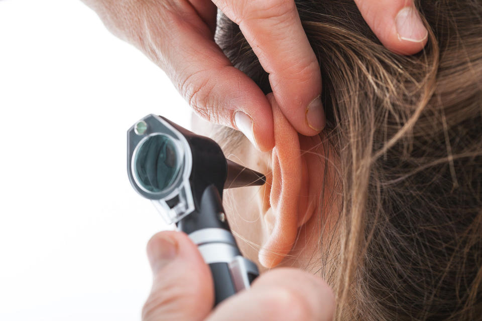 A doctor places an otoscope into a patient's ear