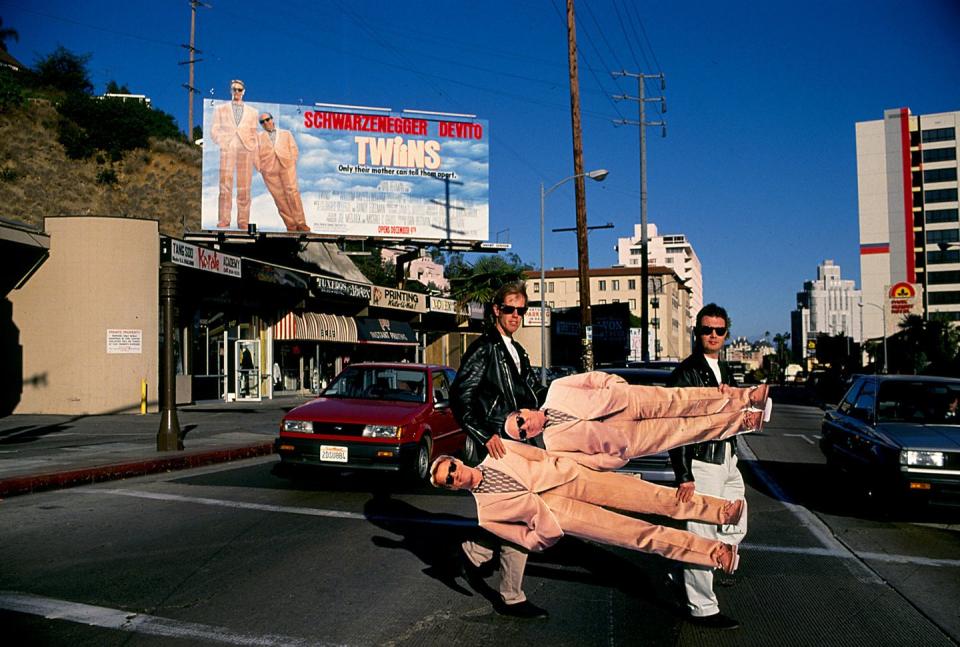 <p>English writers William Davis and William Osborne, known as the two Wills and the writers of the Blockbuster hit <em>Twins</em>, carry life-size cutouts of the film's two lead actors — Arnold Schwarzenegger and Danny Devito — across Sunset Boulevard.</p>