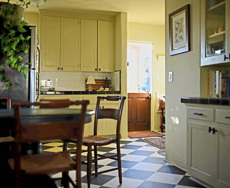 yellow kitchen with black and white checkered floor and wood furniture