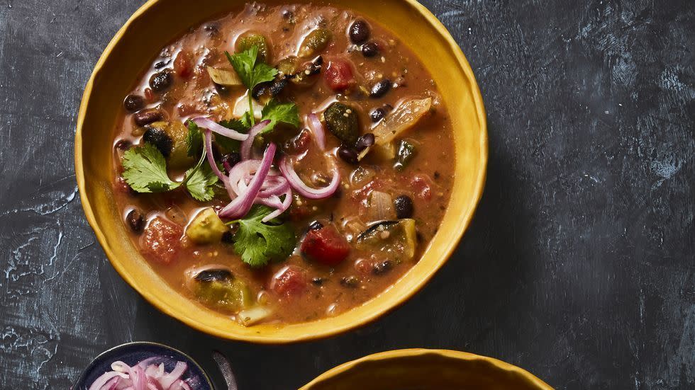 a bowl of bean soup with a bowl of salad next to it