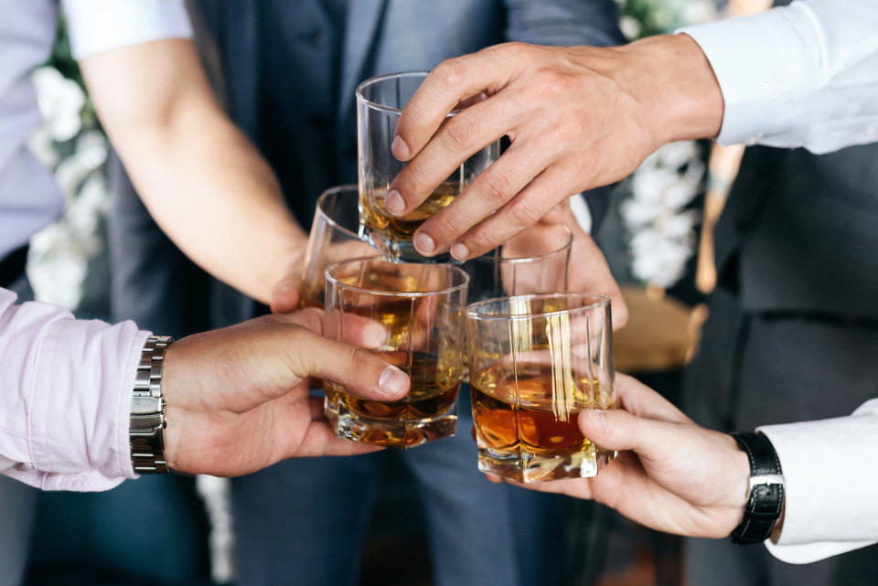 Group of guys friends with glasses of whiskey at a wedding. (Getty Images/iStockphoto)