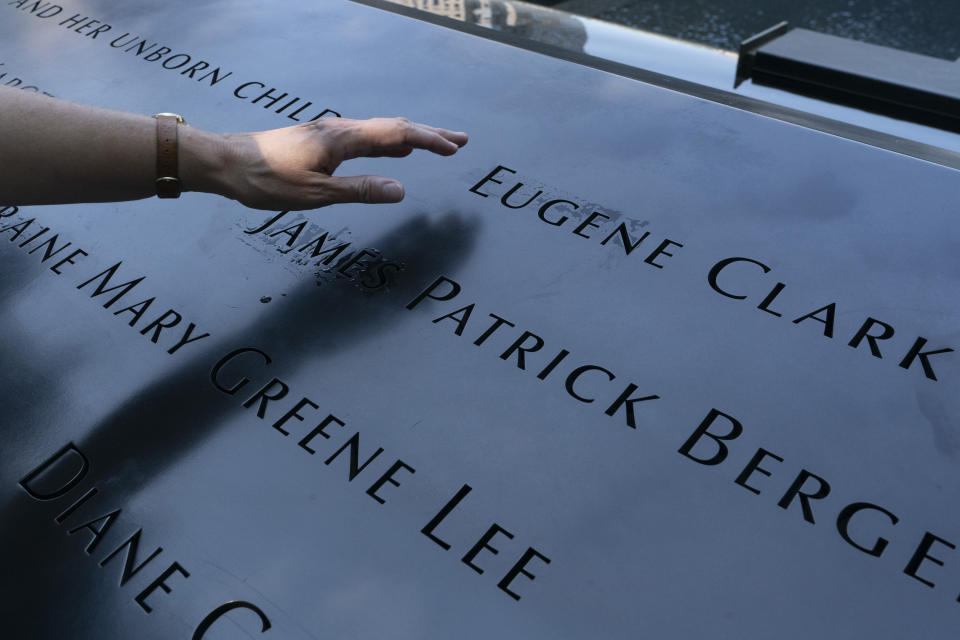 Désirée Bouchat reaches towards the inscribed name of James Patrick Berger at the National September 11 Memorial, Friday, Aug. 6, 2021, in New York. She last saw her co-worker on the 101st floor of the trade center's south tower. Nearly 180 Aon Corp. workers perished on Sept. 11, 2001, including Berger. “Some days, it feels like it happened yesterday,” Bouchat says. (AP Photo/Mark Lennihan)