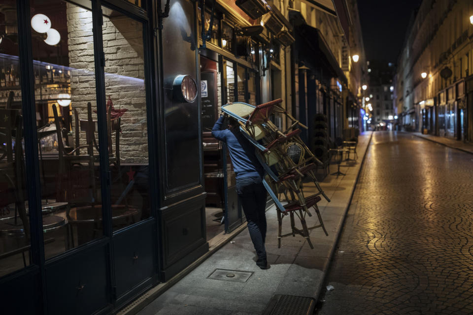 FILE - In this Oct. 17, 2020, file photo, a waiter closes a bar terrace in Paris. Virus cases are surging across Europe and many U.S. states, but responses by leaders are miles apart, with officials in Ireland, France and elsewhere imposing curfews and restricting gatherings even as some U.S. governors resist mask mandates or more aggressive measures. (AP Photo/Lewis Joly, File)