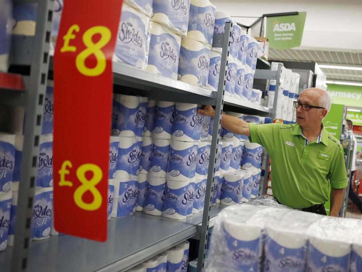 An employee stocks toilet paper along an aisle of an Asda store in Kendal, northwest England. (Reuters)