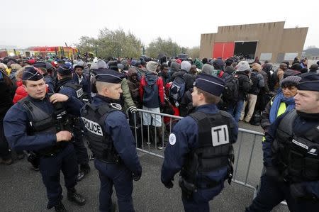 French police stand near as migrants with their belongings queue near barriers at the start of their evacuation and transfer to reception centers in France, and the dismantlement of the camp called the "Jungle" in Calais, France, October 24, 2016. REUTERS/Philippe Wojazer