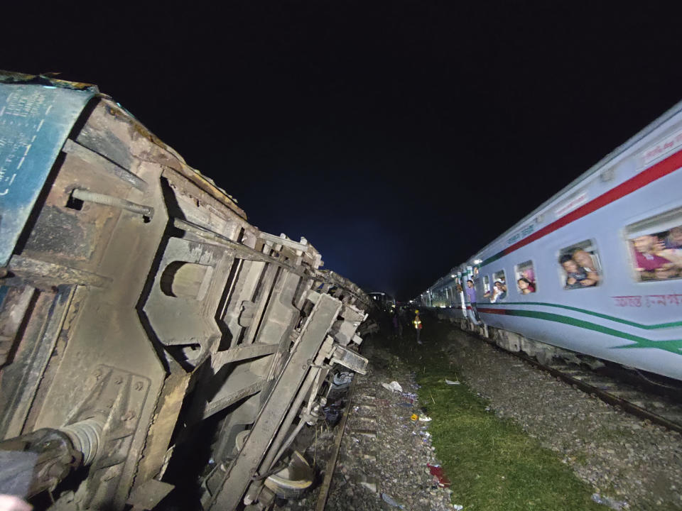 Passengers of a passing train view crashed compartments of a train, at Bhairab, Kishoreganj district, Bangladesh, Monday, Oct.23, 2023. A cargo train has hit a passenger train outside the Bangladeshi capital Dhaka, leaving more than dozen people dead and scores injured. (AP Photo/Mahmud Hossain Opu)