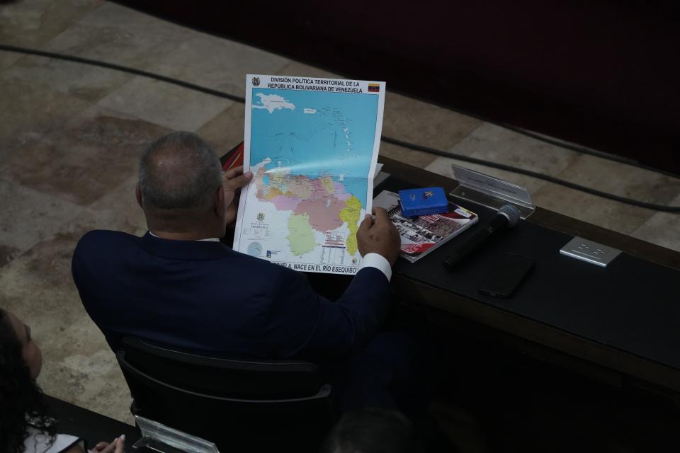 Venezuelan lawmaker Diosdado Cabello, looks at a new map of Venezuela with the Essequibo territory, a large swath of land that is administered and controlled by Guyana but claimed by Venezuela, during a session at the National Assembly in Caracas, Venezuela, Wednesday, Dec. 6, 2023. (AP Photo/Ariana Cubillos)