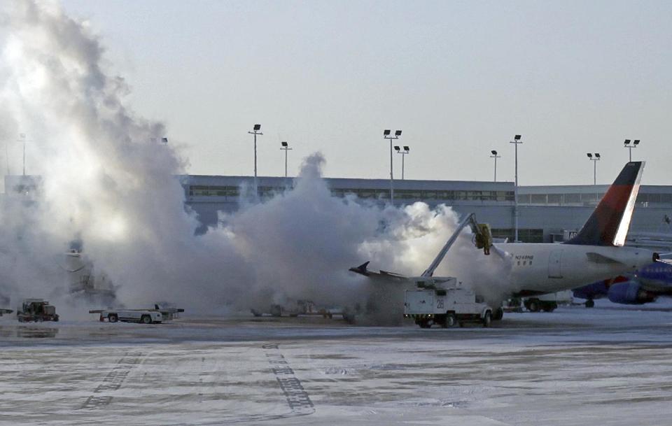 A Delta plane is deiced at Chicago Midway International Airport Monday, Jan. 6, 2014, in Chicago. The bitter weather comes after a heavy snowstorm hit much of the region last week. More than 400 flights were cancelled at Chicago's airports Monday.(AP Photo/Kiichiro Sato)