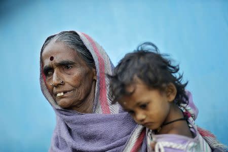 Bedan Bai, 70, the mother of a victim who died after undergoing a sterilization surgery at a government mass sterilization camp, holds her granddaughter Kirti outside her house at Bilaspur district in the eastern Indian state of Chhattisgarh November 15, 2014. REUTERS/Anindito Mukherjee