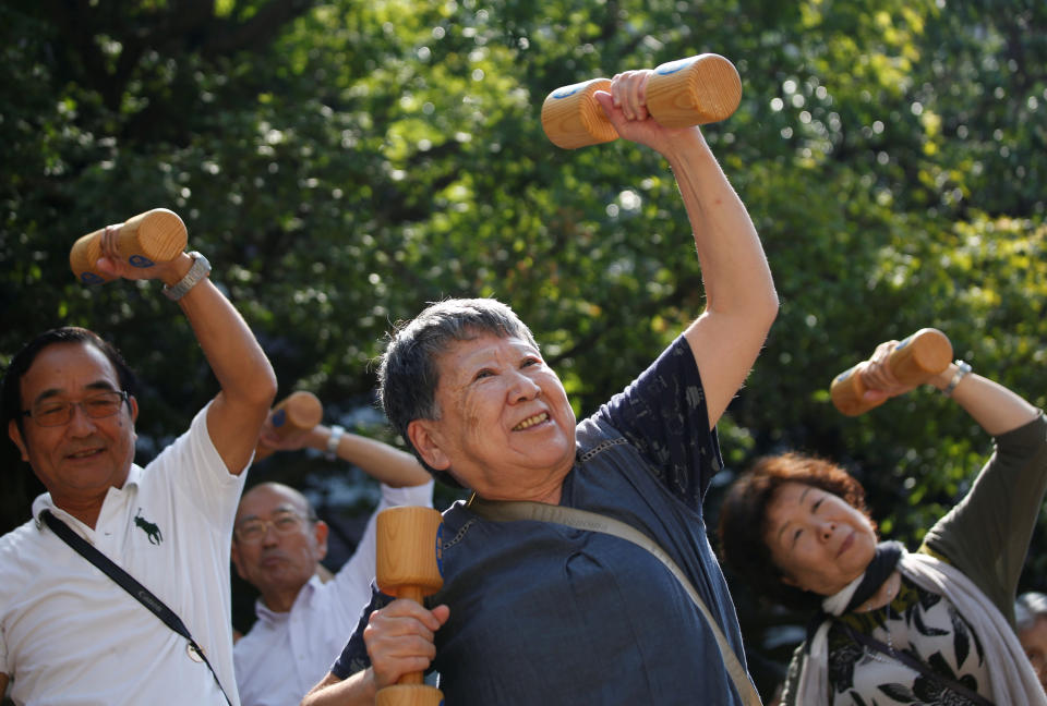 Elderly and middle-aged people exercise with wooden dumbbells during a health promotion event to mark Japan's 