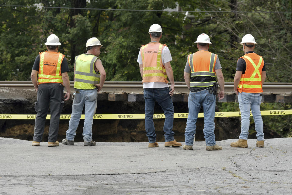 Keolis employees survey the damage to a Commuter Rail train abutment which was washed out Tuesday, Sept. 12, 2023, in Leominster, Mass. after heavy rain fall in the town overnight. (AP Photo/Josh Reynolds)