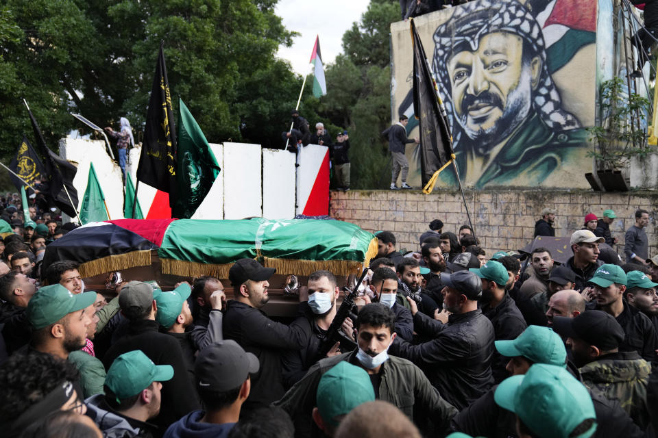 Mourners carry the coffin of Saleh Arouri, one of the top Hamas commanders who was killed in an apparent Israeli strike Tuesday, as they pass in front of a graffiti that shows late Palestinian leader Yasser Arafat, during Arouri's funeral in Beirut, Lebanon, Thursday, Jan. 4, 2024. (AP Photo/Hussein Malla)