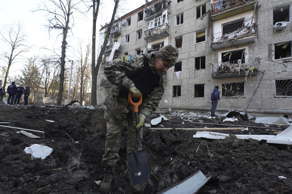 A police officer inspects a crater in front of a damaged residential building that was hit by a Russian strike in Kharkiv, Ukraine, Wednesday, March 27, 2024. (AP Photo/Andrii Marienko)
