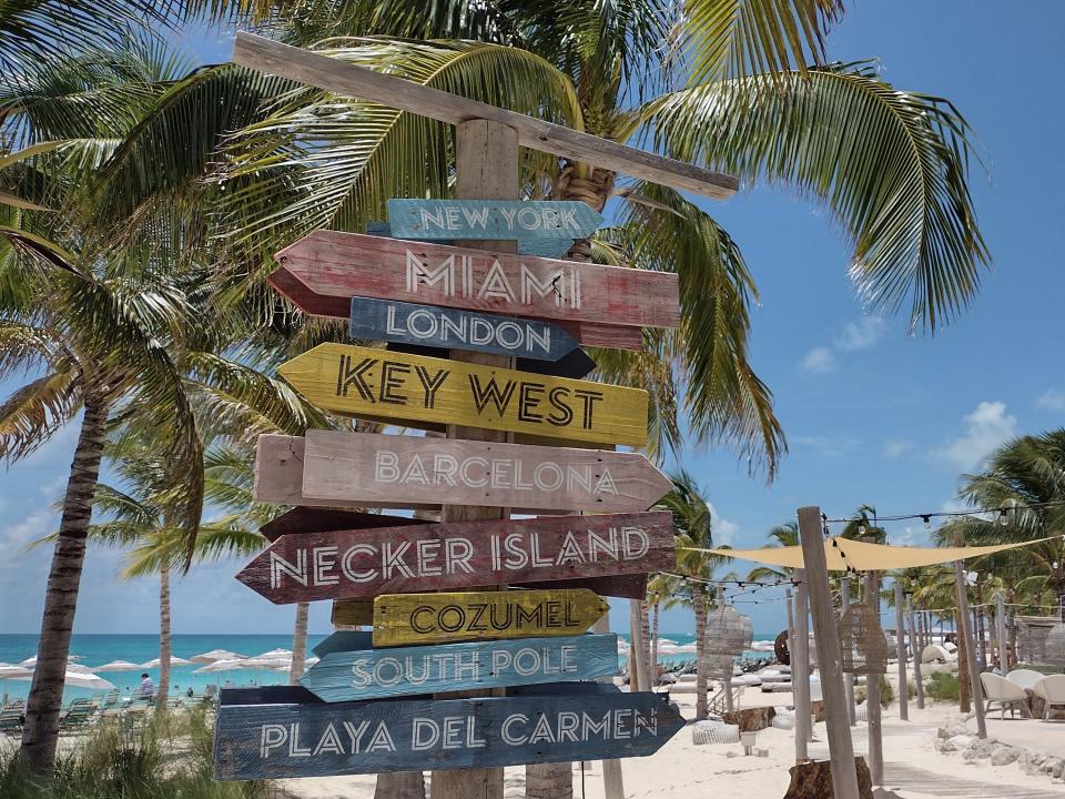 signs pointing to various tropical locations on the beach in key west florida
