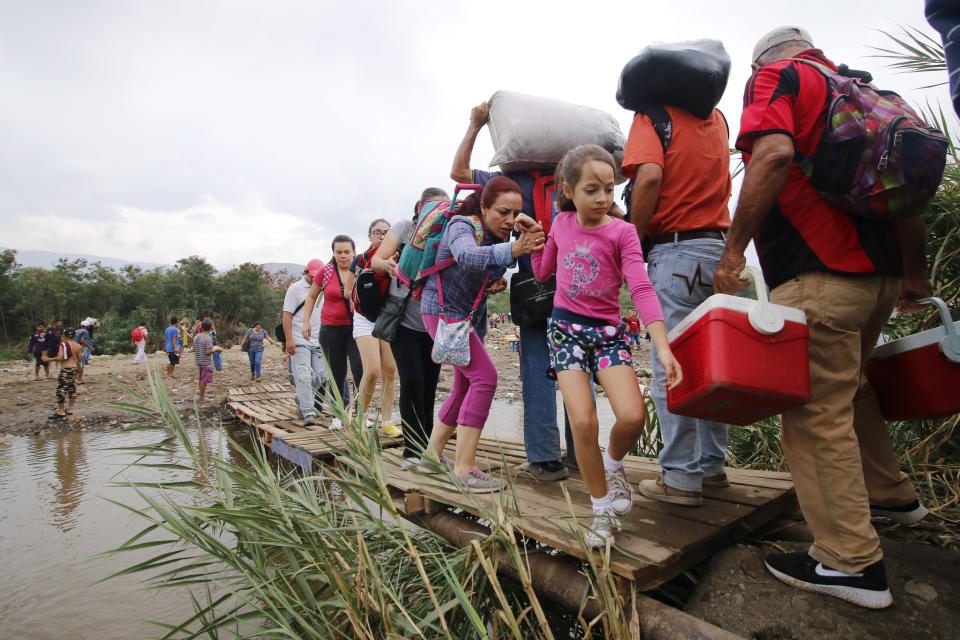 People cross a makeshift bridge in the Tachira River, from Venezuela into Colombia, near the Simon Bolivar International bridge which Venezuelan authorities only open to students and the sick in Cucuta, Colombia, Tuesday, March 12, 2019, on the border with Venezuela. People crossing the river are using makeshift bridges as the water level grows with the approaching rainy season. (AP Photo/Schneyder Mendoza)