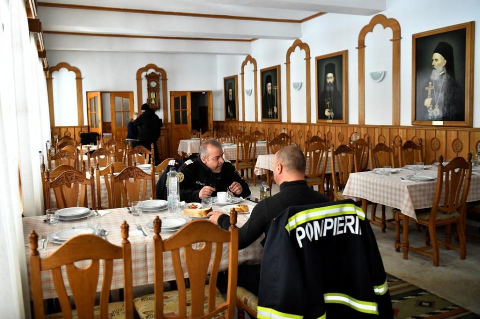 Firefighters eat lunch at the monastery where they are staying while working on the Siret border (Reuters)