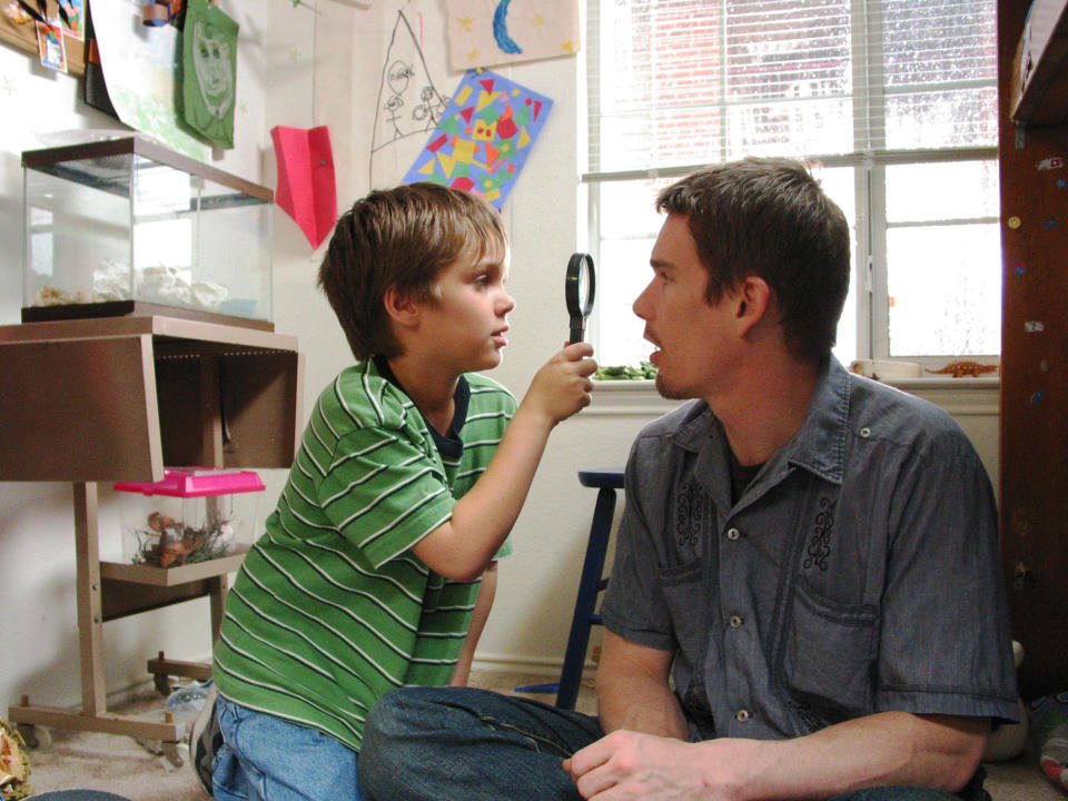 Ellar Coltrane looks into Ethan Hawke's eyes with a magnifying glass