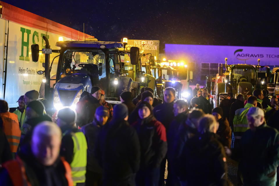 Farmers stand together with truck drivers at a meeting point shortly before they set off on a protest action in Uelzen, Germany, Monday, Jan. 8, 2024. Farmers blocked highway access roads in parts of Germany Monday and gathered for demonstrations, launching a week of protests against a government plan to scrap tax breaks on diesel used in agriculture.(Philipp Schulze/dpa/dpa via AP)